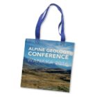 Tote bag with blue handles featuring an image of a mountainous landscape. The text Alpine Geology Conference, Wanaka 2016 is printed in white and light blue across the top.