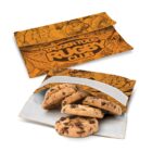 Two reusable snack bags in orange with a floral and leaf pattern. The top bag has TAGGER TODS RUGBY CLUB written on it. The lower bag is open, revealing chocolate chip cookies inside.