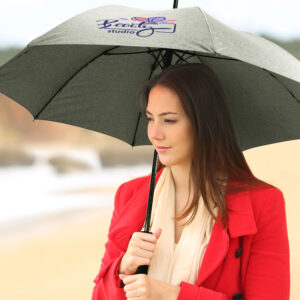 Woman in a red coat with a custom umbrella on a beach.