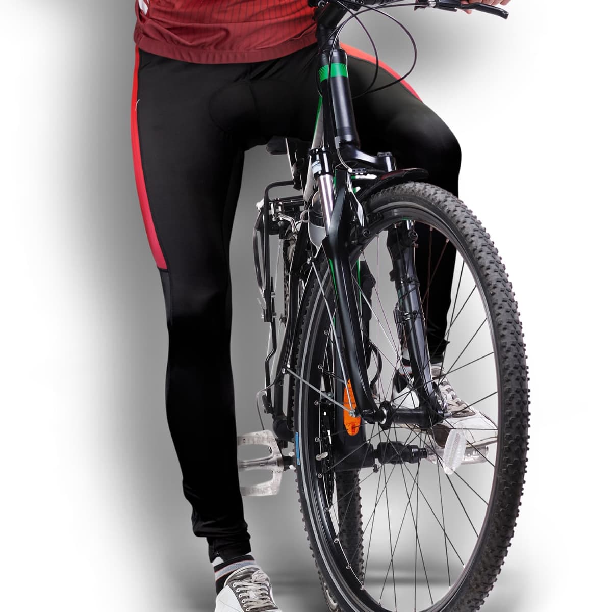 A cyclist wearing black and red athletic clothing is on a mountain bike, positioned with one foot on the pedal and the other on the ground. The background is a simple white to gray gradient.