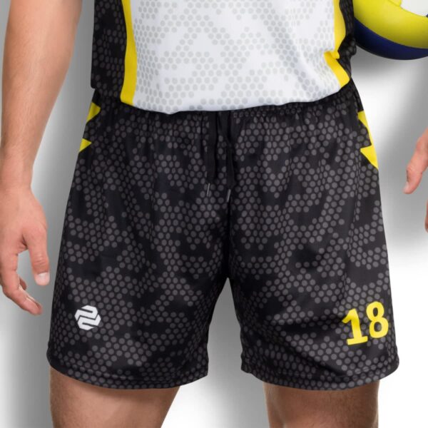Person wearing a sports uniform with a gray patterned shirt and black shorts, featuring yellow accents and a number 18. They are holding a blue and yellow volleyball.