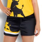 Person wearing a yellow shirt with a black bull graphic and black shorts featuring a similar bull design with yellow and white stripes. Hand on hip, standing against a white background.