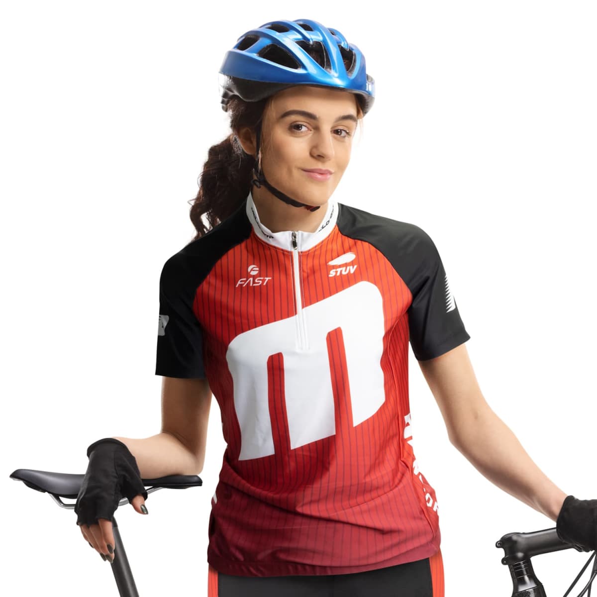 A cyclist wearing a blue helmet and red cycling jersey with white and black accents holds a bicycle. She smiles confidently, with gloves on her hands. The background is white.