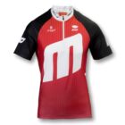 Red and black cycling jersey with white accents, featuring a large white letter M and logos reading FAST and STUV. The design also includes small graphic elements on the sleeves.