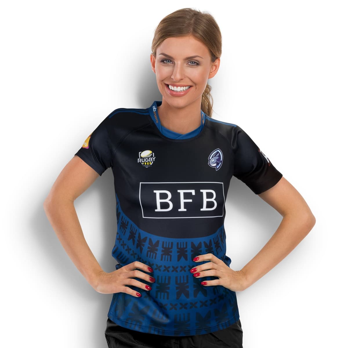 A smiling woman wearing a dark blue rugby jersey with BFB and a logo on the front. The shirt features a patterned design on the lower half. Her hands are on her hips, and she stands against a plain white background.