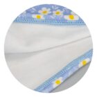 Close-up of a fabric with a floral pattern, featuring white daisies with yellow centers on a blue background. The edge is sewn with light blue thread, and the fabrics underside is a soft white material.