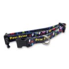 Colorful dog collar with cartoon characters and Paw Print text. Features a black plastic buckle and metal D-ring. The design includes bright colors like red, blue, and green, set against a dark background.
