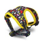 Dog harness with a colorful pattern featuring various icons like bones, hearts, and stars. The harness is primarily black with vibrant yellow outlines and adjustable straps. The text Paw Print is visible on some parts of the straps.