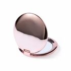 Rose gold compact mirror, open, with a reflective surface.