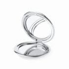 Open round silver compact mirror with dual reflective surfaces.