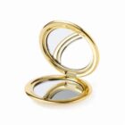 Gold compact mirror open, showing two reflective surfaces.