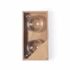 Two transparent glass teacups in a cardboard box with a corner partially open.