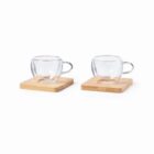 Two clear glass cups with handles on square wooden coasters against a white background.