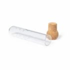 A clear glass test tube lying next to a round cork stopper on a white background.