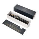 A black and gold Parker pen in an open gift box with a branded card and packaging.