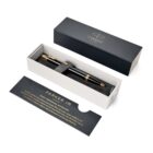 A black and gold Parker pen in a gift box with a card and dark lid beside it.