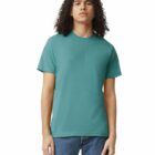 A person wearing a teal t-shirt and jeans standing against a white background.