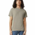 Person with curly hair wearing a plain taupe t-shirt and blue jeans, standing against white background.