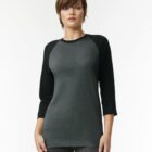 Person wearing a grey and black raglan sleeve shirt, standing against a plain background.