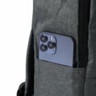 Smartphone with triple-lens camera partially visible in grey backpack pocket.
