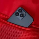 Smartphone with triple camera in red mesh pocket.