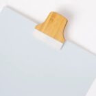 Wooden clip holding a stack of white papers.