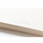 Close-up of notebook edge with Recycled Milk Carton subtly embossed on cover.