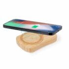 Smartphone charging wirelessly on a wooden charging pad, battery icon visible on screen.