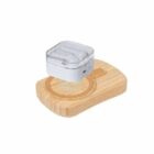 Wireless earbuds in a clear case, placed on a small wooden charging pad.