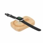 Smartwatch with a black band charging on a wooden wireless charging pad.