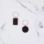 Two keychain rings with black, one rectangular and one circular, on a marble surface.