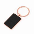 Rectangular black keychain with a rose gold ring on a white background.