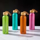 Four colorful metal water bottles with wooden caps on a marble surface.