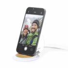 Smartphone on a stand displaying a selfie of a smiling couple in winter clothing.