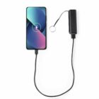 Smartphone charging with a power bank connected by a black cable.