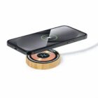 Smartphone charging wirelessly on a round wooden charging pad.