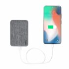 Smartphone connected to a gray textured power bank with a charging cable.