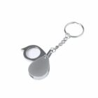 Silver magnifying glass keychain with a teardrop-shaped cover on a white background.