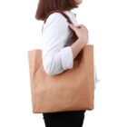 Person in white shirt carrying a large brown paper bag over their shoulder.