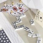 Dominoes, playing cards, and dice arranged on a white surface.