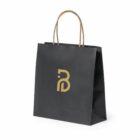 A black paper shopping bag with brown handles and a gold logo on the front, set against a white background.