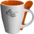 White mug with orange interior and spoon, featuring a customizable logo and slogan.