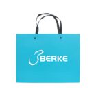 Teal shopping bag with black handles and BERKE logo in white.