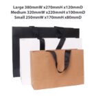 Three shopping bags of different sizes: black, white, and brown with black handles.