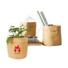 Three brown paper pots, holding a plant, tissues, and stationery, stacked on books.