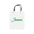 White paper bag with black handles and green BERKE logo on the front.