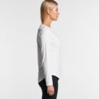 Person in white long-sleeve shirt and black pants, standing in profile against a white background.