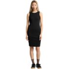 Woman in a sleeveless black dress with black sneakers standing against a white background.