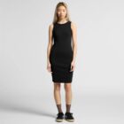 Woman in a sleeveless black dress and sneakers stands against a plain light background.
