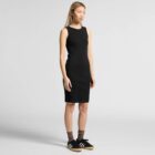Young woman in a sleeveless black dress with sneakers and socks, standing against a plain background.